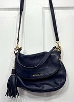 Front view of blue Michael Kors Bedford bag with strap and tassel