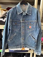 Front view of blue GWG denim jacket hanging
