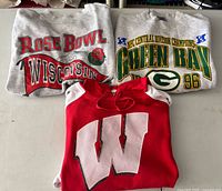 Group shot of three vintage sweatshirts: Packers 1996 champ crewneck, Wisconsin Rose Bowl crewneck, Wisconsin hooded sweatshirt