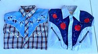 Both shirts folded side by side showing overall design, colors and embroidery