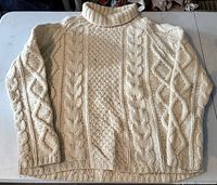 Front view of cream wool cable-knit turtleneck sweater