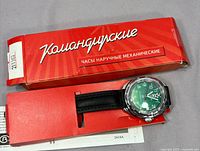 Watch in open red Komandirskie box showing dial and strap