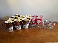 Full lot view showing all 10 Smirnoff mugs, 4 Tabasco glasses, 4 McDonald’s snifters