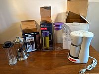 All four beverage makers with their boxes on tabletop