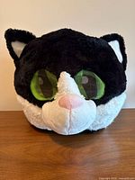 Front view of black and white cat head costume mask showing green eyes and pink nose