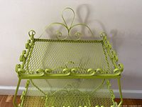 Top view of lime green wrought iron plant stand showing scroll detail and mesh shelf