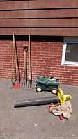 Group shot of blower vacuum, tube, bag, four long-handle tools and rolling stool