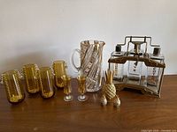 Entire lot showing decanters in caddy, pitcher, amber tumblers, cordial glasses, pineapple pieces