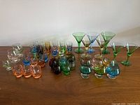 All 45 coloured cordial glasses arranged on table
