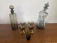 Entire lot showing both decanters, four matching hourglass cordial glasses, one small straight cordial glass