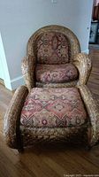Front view of rattan armchair with ottoman showing cushions and overall design