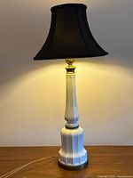 white fluted ceramic lamp with black shade, cord visible