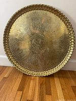 Full view of round brass tabletop leaning on wall