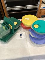 group of Tupperware containers in various colors and shapes on table