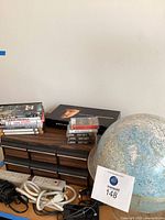 Full lot showing cassette cabinet, DVDs, CDs, cassettes, power strips, cables, TV devices and globe