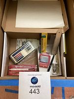 Open box showing entire lot with calligraphy set, ink, pens, parchment