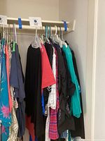 Clothing on hangers left side of closet rod