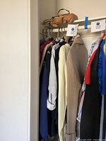 Closet view showing multiple women’s garments on hangers and tan purses above rod