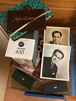 Stack showing encyclopedias, Waterford guide, journals, two Cross pen boxes, two actor photos