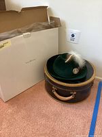 Hat on closed round case beside white box