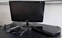 Samsung monitor, Toshiba Blu-ray player, remote and cables on tabletop