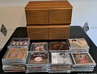 Stacked CDs and two wooden CD cabinets showing size and condition