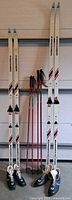 Full view showing two pairs skis, two pairs poles, two pairs boots