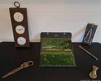 Group shot showing all items: drafting set, weather station, extra compass, letter opener, hand paper holder