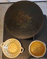 Overview of table top with floral painting, colander and pot