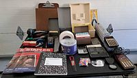 Overall view of calculators, paper, stapler, tape dispenser, clipboard and other office items
