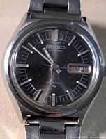 Front view of Seiko watch showing dial, day-date window and scratches