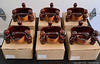 Six matching triangular tiki bowls on boxes, full view