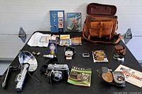 Overall view of all camera, flash, meter, bulbs, filters, manuals and bag on table