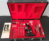 Open case showing microscope, glassware, tools