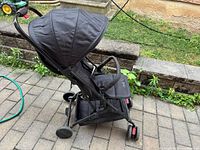 Side view of black Jovial foldable stroller showing canopy, frame and wheels