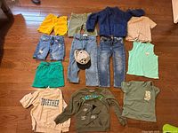 All 13 clothing items and hat laid out on floor