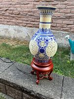 Full view of porcelain vase lamp on wood stand showing design and cord