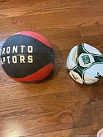 Toronto Raptors basketball beside deflated soccer ball on floor