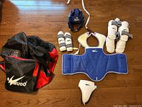 Full set laid out: chest protector, headgear, forearm guards, shin guards, groin guard, duffel bag