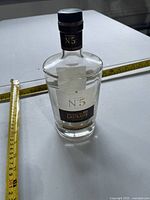Front view of bottle beside tape measure indicating height