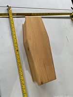 Top view of coffin-shaped wooden box next to tape measure showing size