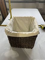 Overall view of woven cube basket with cloth liner and tape measure showing dimensions