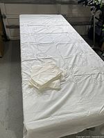full view of white cutwork tablecloth on table with stacked napkins