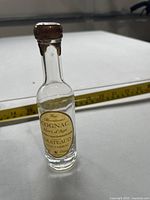 Front view of Grateaud Cognac miniature bottle with measuring tape for scale