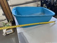 Blue plastic cat litter box with tape measure indicating length