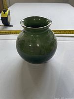 Front view of green glazed pottery vase with tape measure for scale