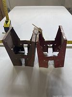 Front view of both steel sawhorse brackets with tape measure for scale