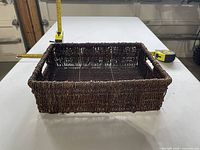 overall view of rectangular wicker basket with tape measure showing length and width