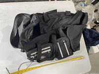 Overall view of the black nylon shoulder bag with tape measure showing size