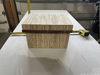 Front view of rectangular storage box with lid and measuring tape for scale